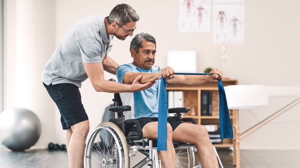 A man in a wheelchair works with a physical therapist following a spinal cord injury