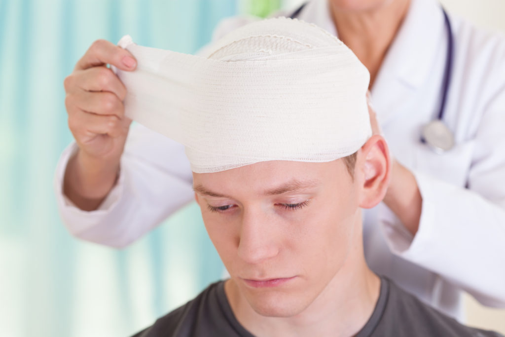 A doctor wraps a man's head with bandages after a brain injury