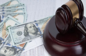 A gavel sits on a stock document and several 100 dollar bills representing a contingency fee