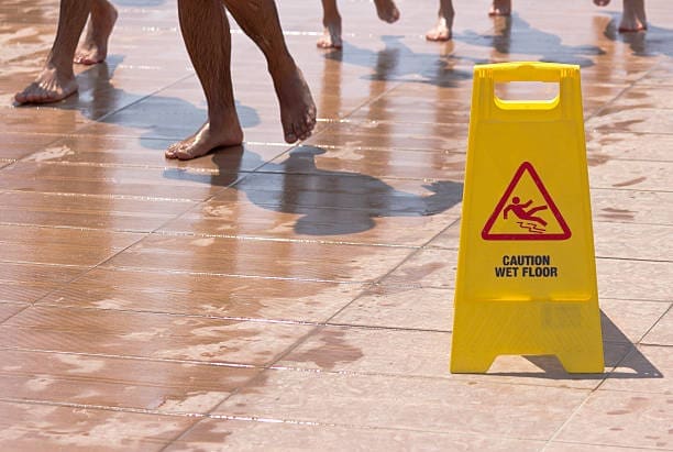 Caution wet floor sign at a public pool to comply with swimming pool accident liability