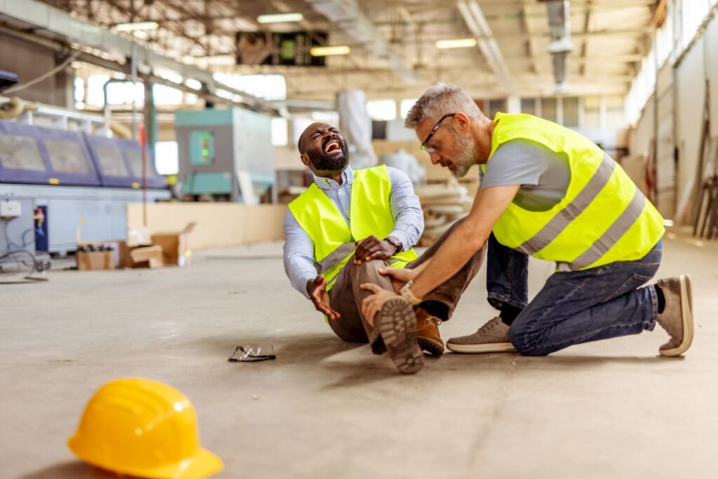 Worker in a hard hat experiencing a work-related injury at a job site